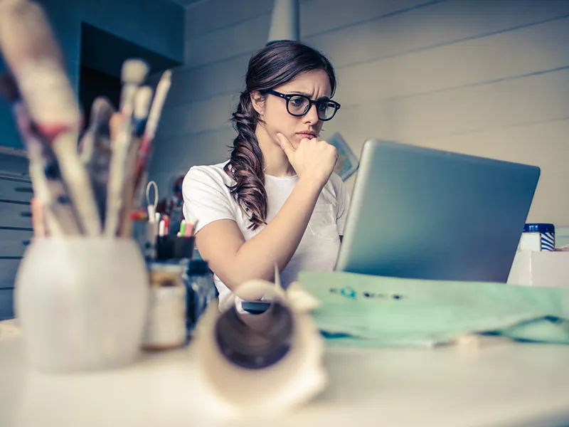 Girl sitting at desk, staring at laptop.