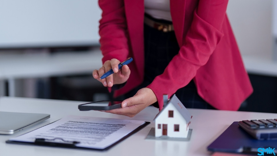 Women leaning over desk, on phone. Paperwork surrounds her.
